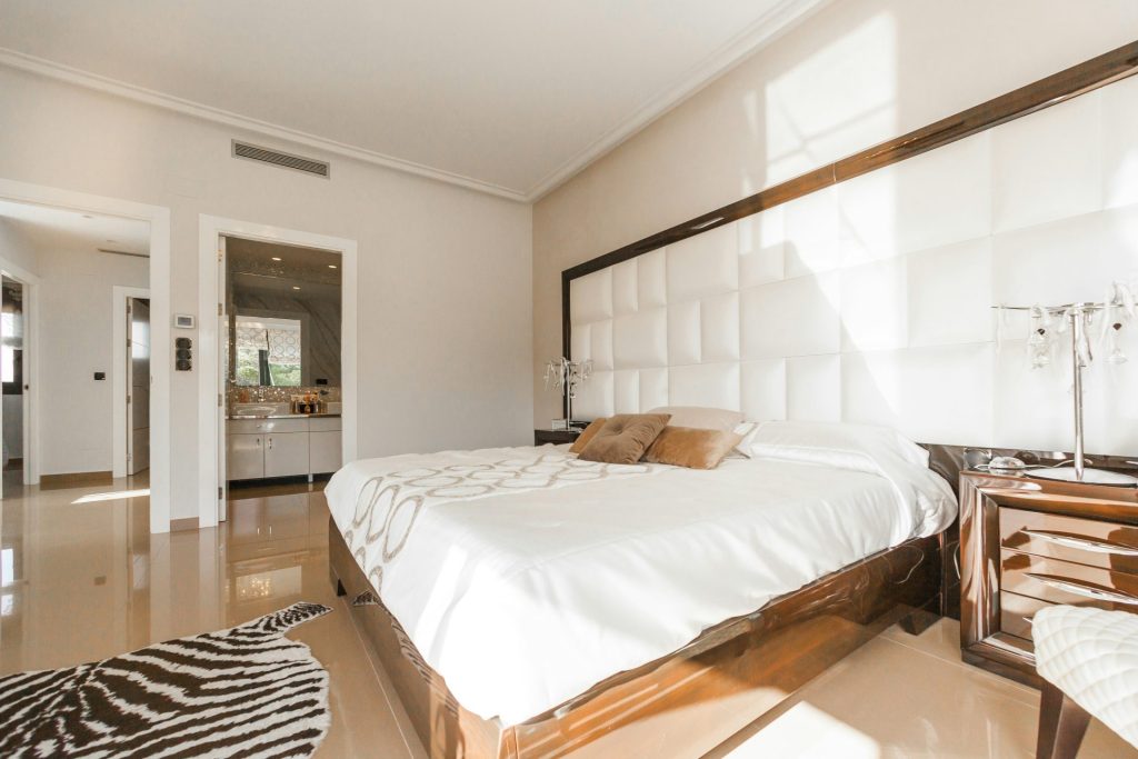 braunes Holzbettgestell mit weißer Decke neben braunem Holz-Nachtisch